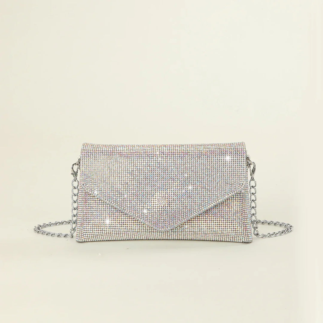 Silver rhinestone envelope clutch bag with chain strap on beige background