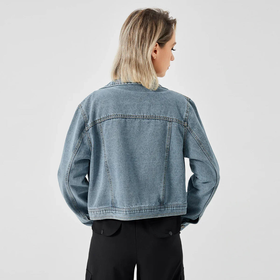 Back view of woman wearing light blue denim jacket and black pants against white background