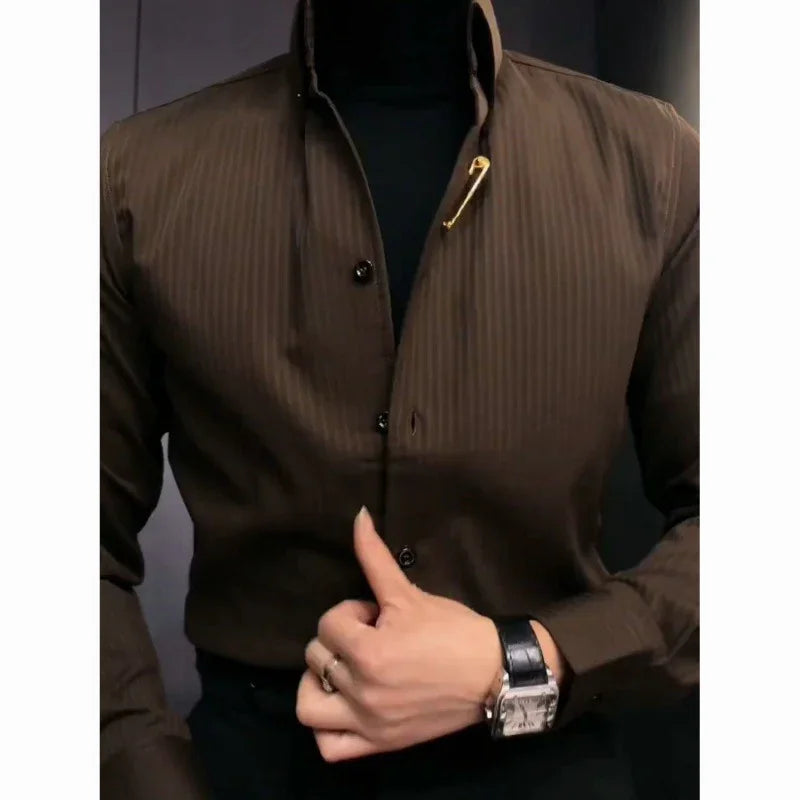 Close-up of person buttoning brown striped shirt with gold safety pin detail, wearing black leather watch