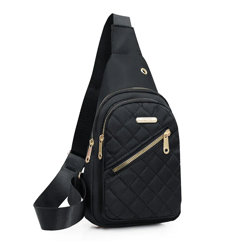 Black quilted sling bag with gold zippers and adjustable strap on white background