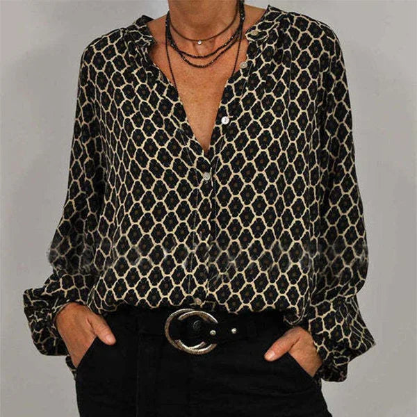 Woman wearing black and beige geometric patterned blouse with long sleeves and black pants with round silver buckle belt