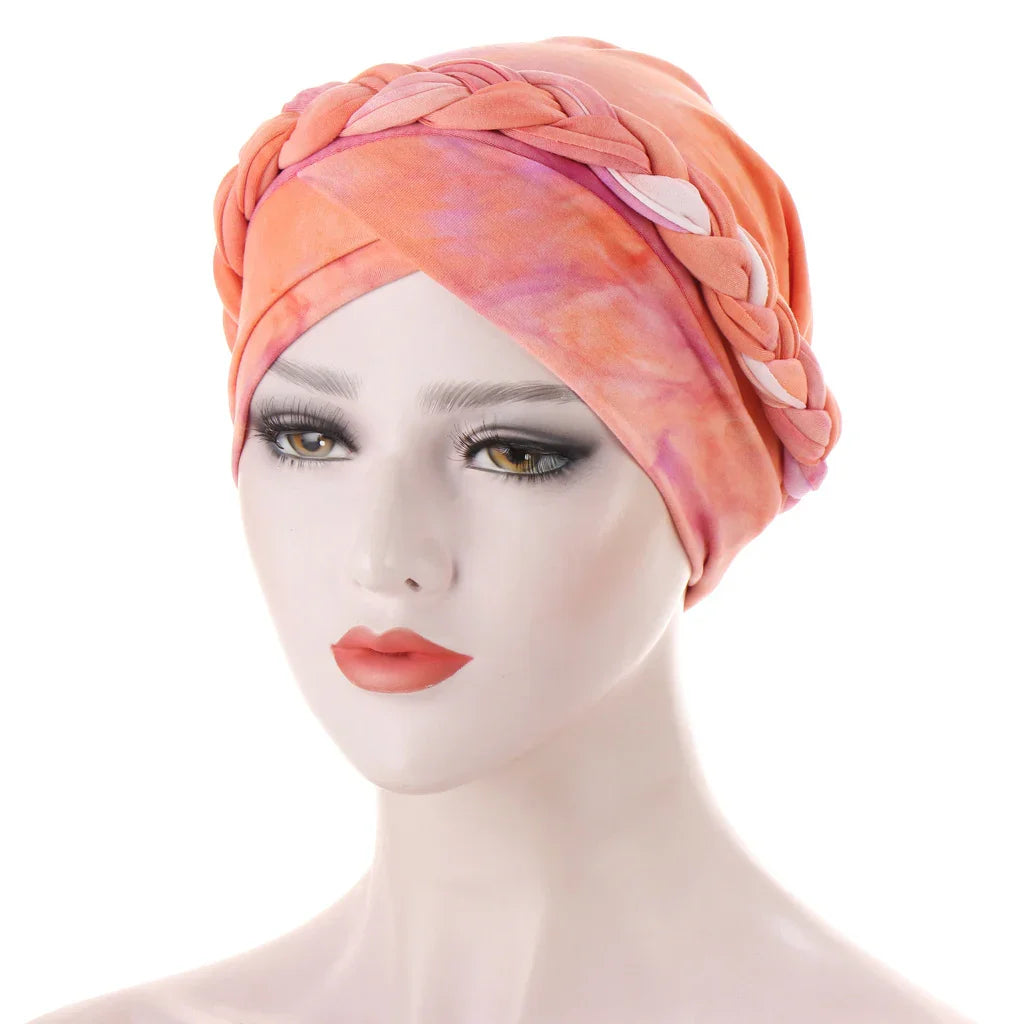 Woman mannequin wearing coral and pink braided turban headwrap against white background
