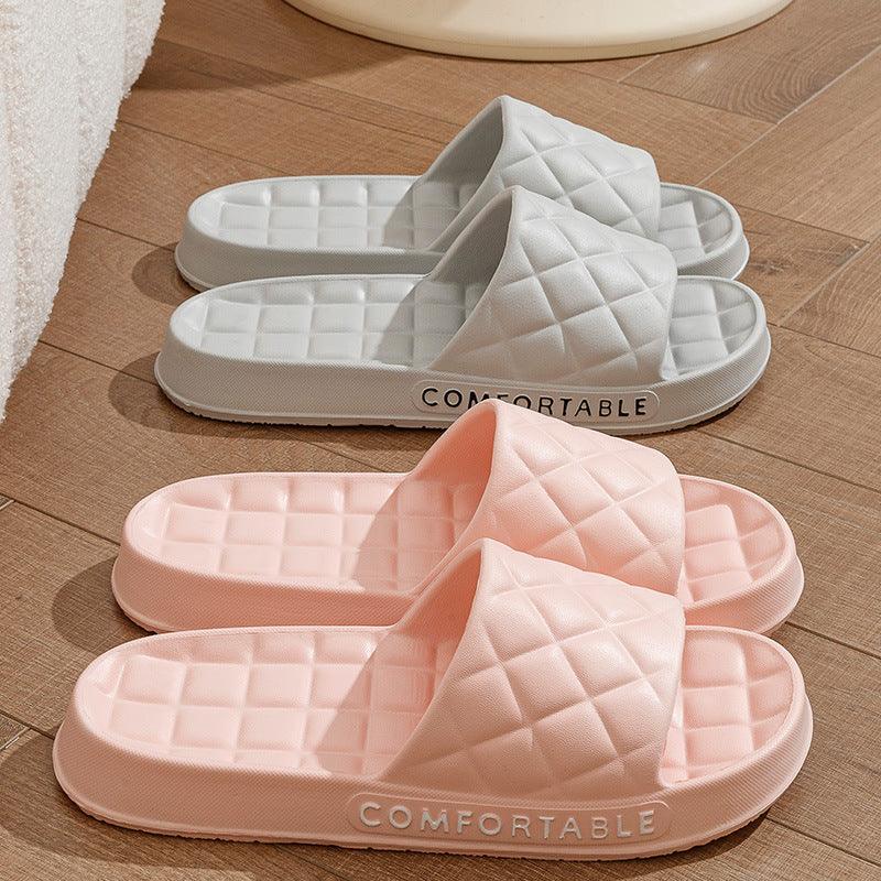 Pair of pink and gray quilted slide slippers with comfortable sole on wooden floor