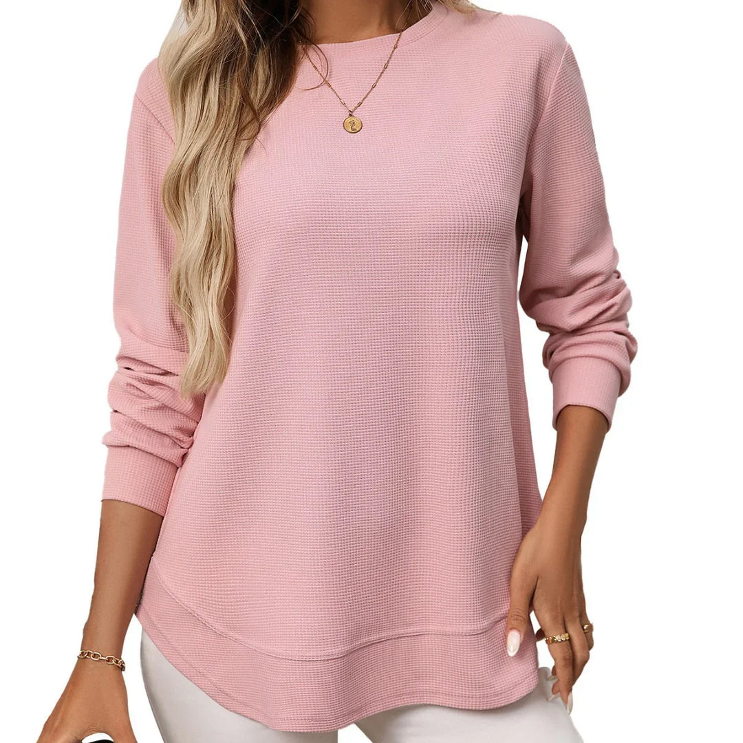 Woman wearing a pink waffle knit long sleeve casual top with white pants and gold jewelry