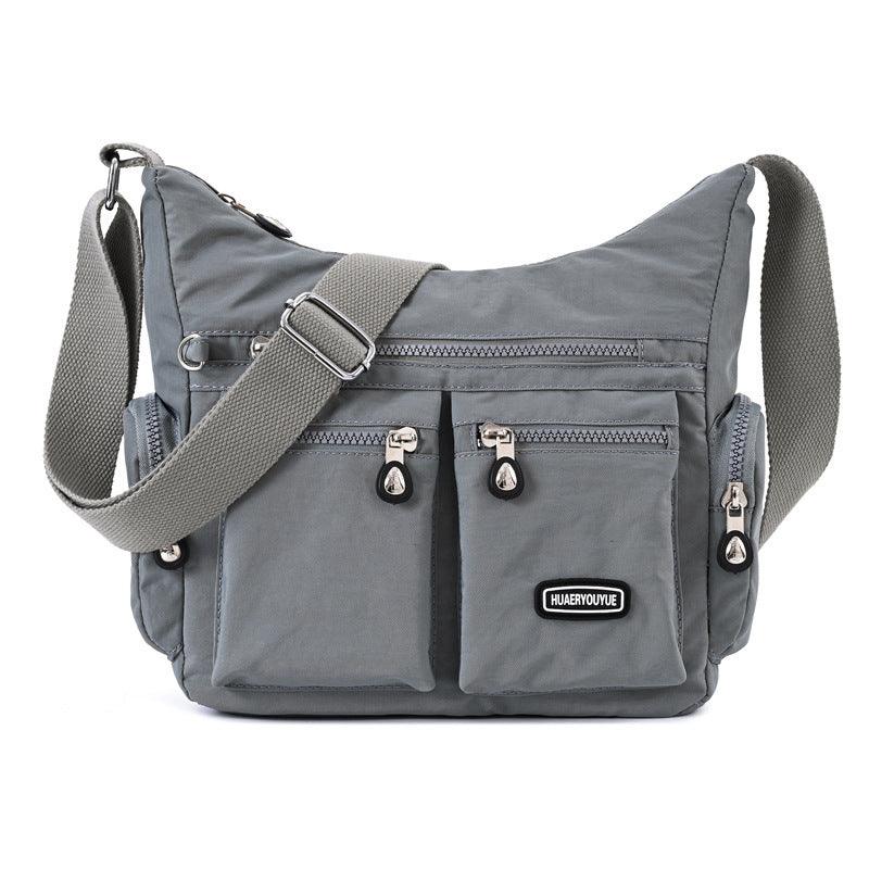 gray crossbody bag with multiple zippered pockets and adjustable shoulder strap