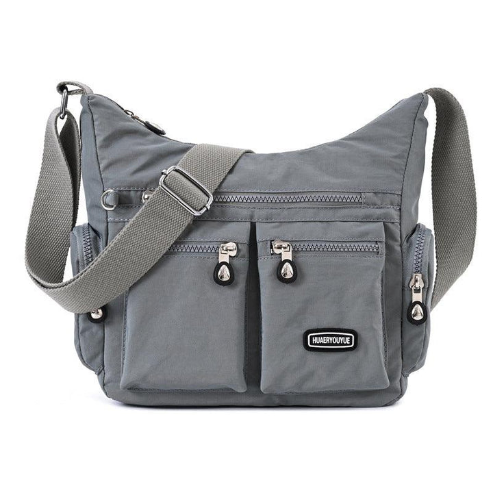 gray crossbody bag with multiple zippered pockets and adjustable shoulder strap