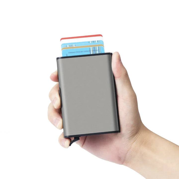Hand holding a gray minimalist slim wallet with cards partially visible