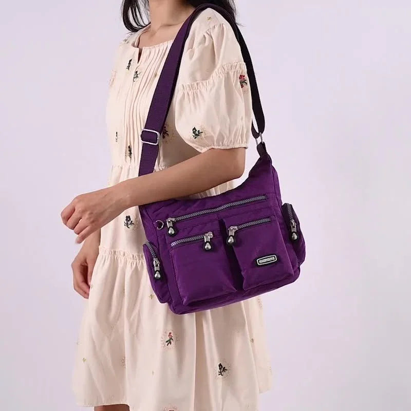 Woman wearing cream floral dress carrying a purple multi-pocket crossbody bag