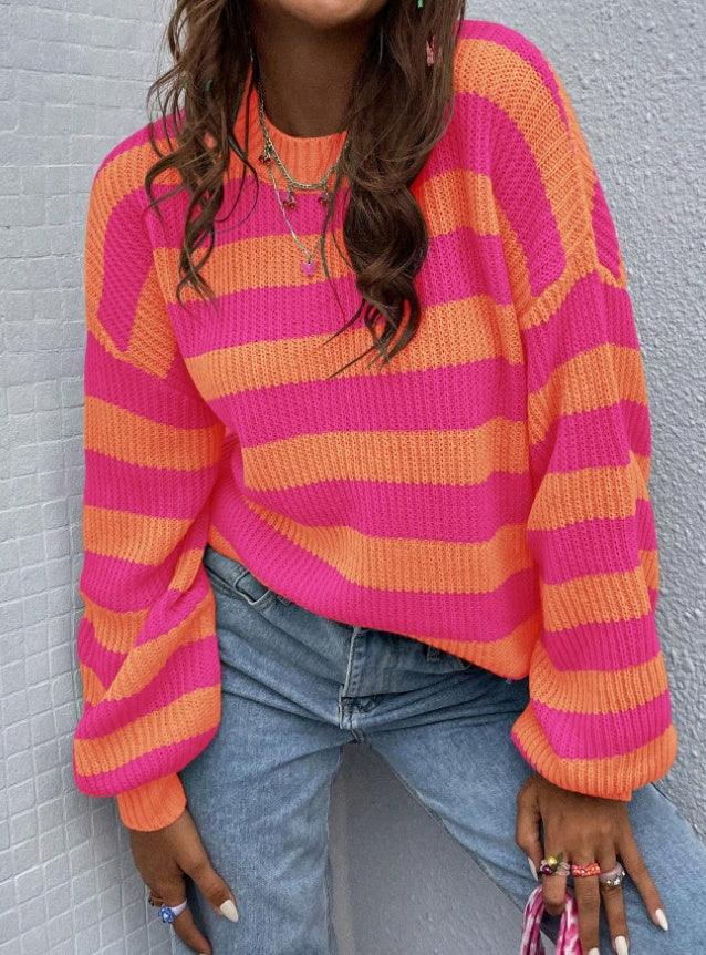 Woman wearing bright pink and orange striped sweater with blue jeans and colorful rings