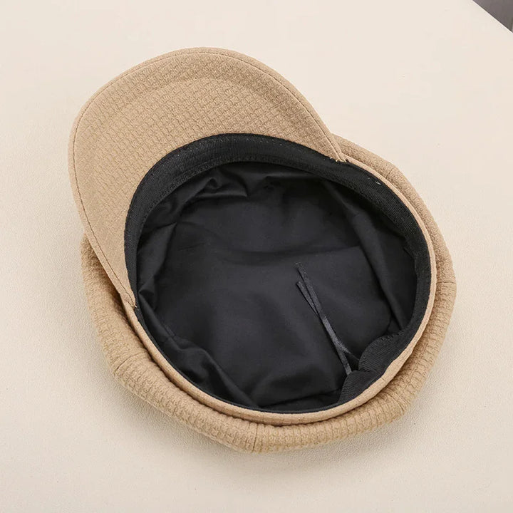 Beige textured winter cap with black soft inner lining on light surface