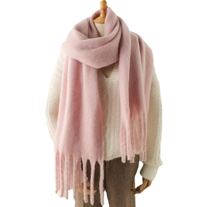 Soft pink oversized scarf with fringes on a mannequin wearing a white knit sweater and brown pants