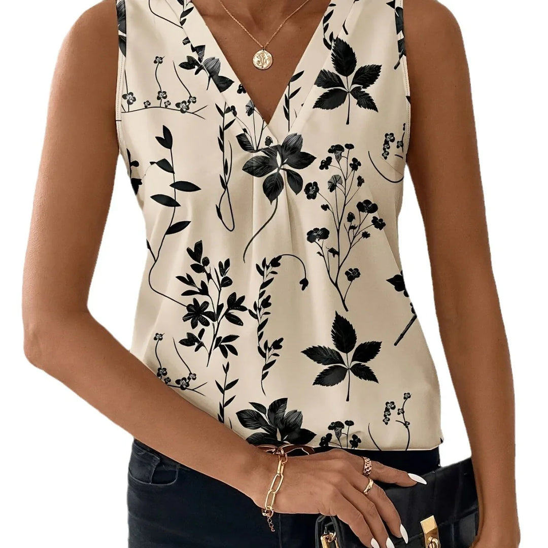Woman wearing sleeveless cream blouse with black floral print and V-neck, accessorized with gold necklace and bracelet