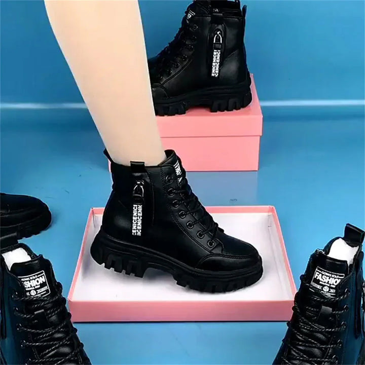 Black combat boots with chunky soles and zippers displayed on pink boxes on a blue surface