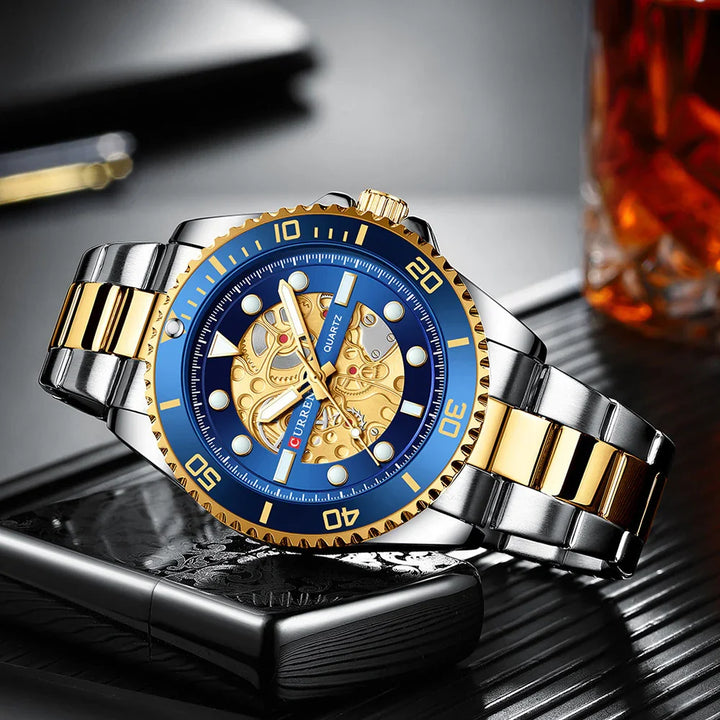 Luxury two-tone gold and silver wristwatch with blue bezel and skeleton dial on leather surface