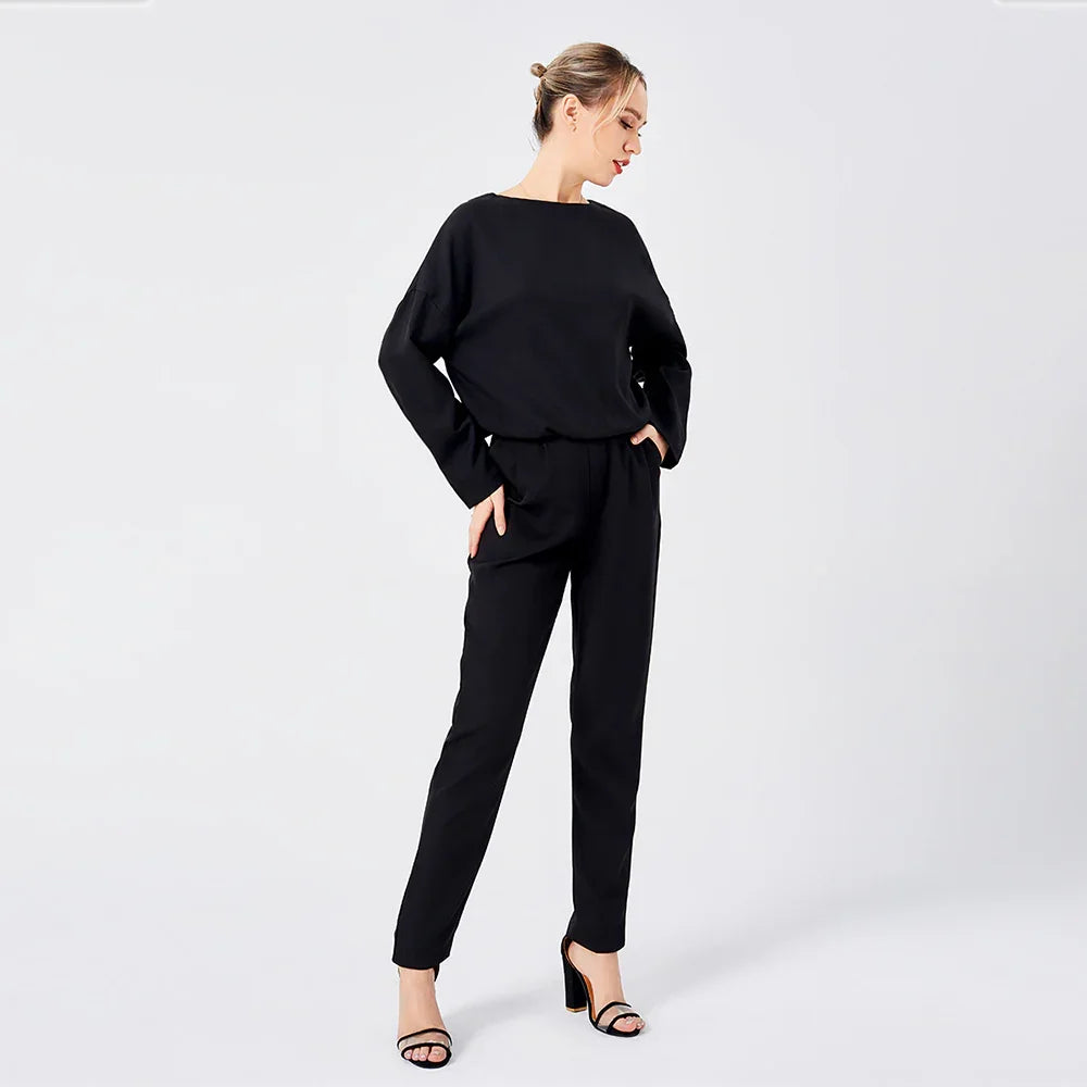 woman wearing black long sleeve top and black pants paired with black high heel sandals on white background