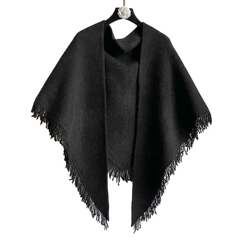Black wool poncho with fringed edges hanging on a black hanger with white flower detail