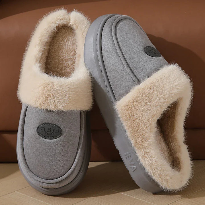 Gray slip-on slippers with beige faux fur lining and EVA sole on wooden floor