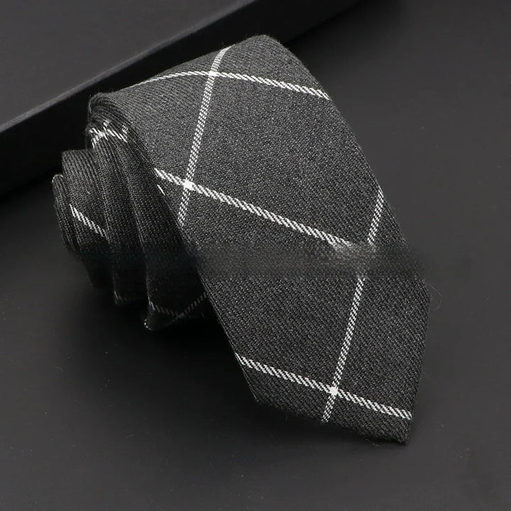 Rolled dark gray men's necktie with white checkered pattern on black background