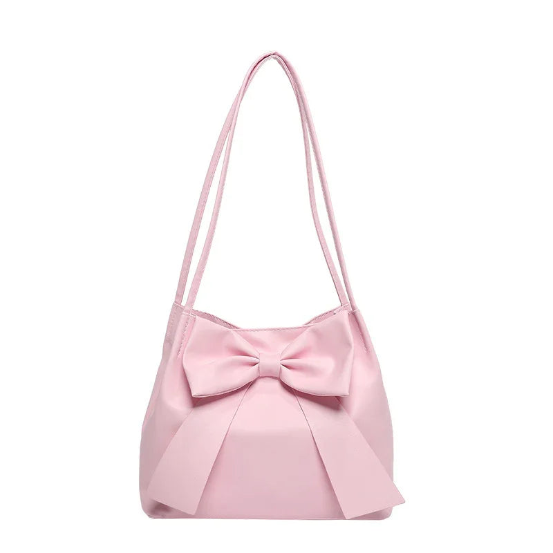 pink shoulder bag with large decorative bow and double straps on white background