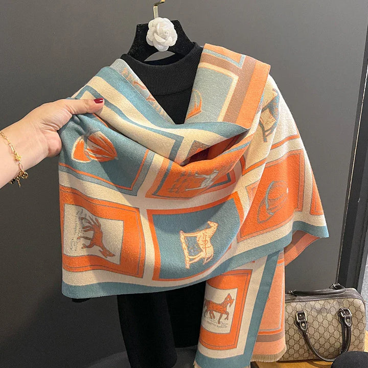 Soft wool scarf with orange and blue panels featuring horse and shell motifs, draped over black mannequin