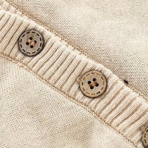 Close-up of beige knitted fabric with ribbed edge and two brown four-hole buttons