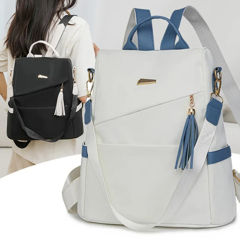 Modern white and black backpacks with tassel charms, blue accents, and adjustable straps for women