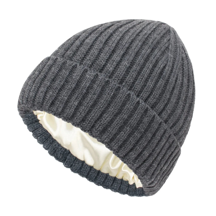 Dark gray ribbed knit beanie hat with white satin lining on white background