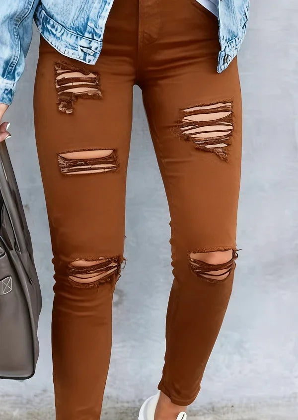 Close-up of brown distressed skinny jeans with ripped detailing worn with blue denim jacket and white sneakers