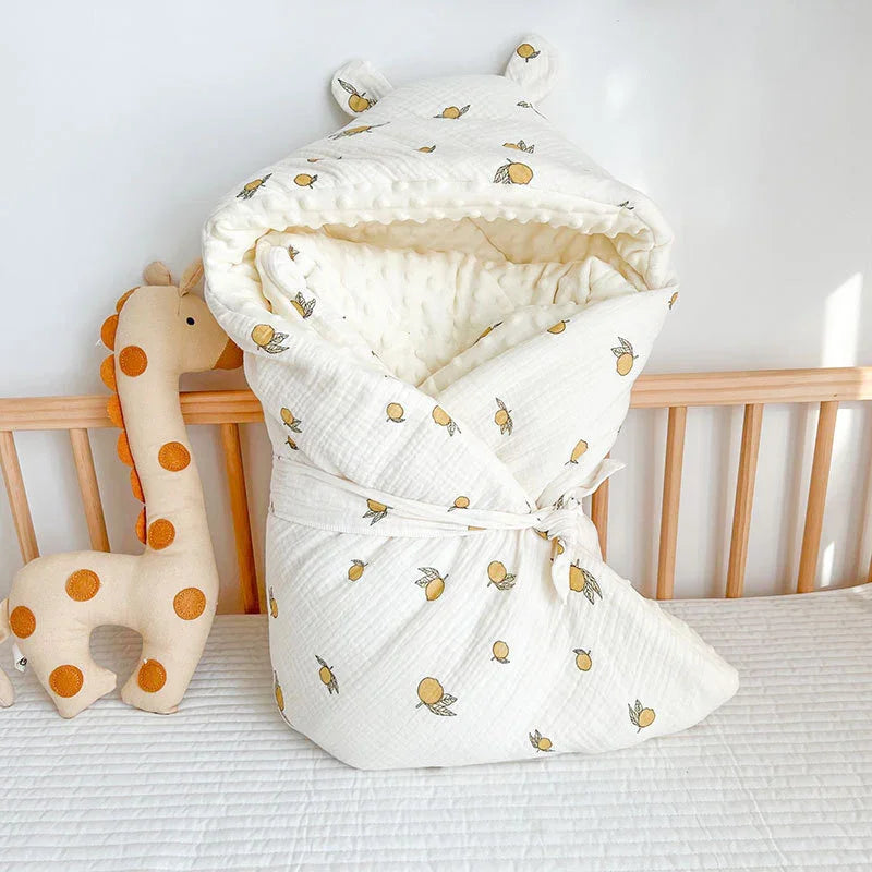 White baby swaddle blanket with yellow fruit pattern and bear ears on wooden crib with giraffe plush