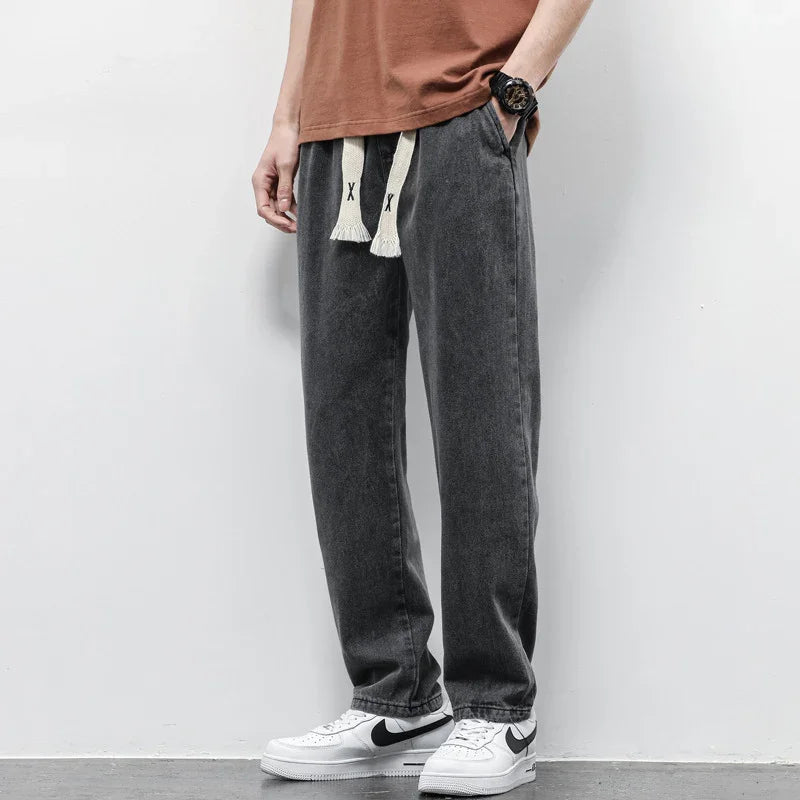 Man wearing casual faded black jogger pants with white drawstrings and white Nike sneakers