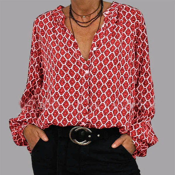 Woman wearing a red and white patterned long-sleeve blouse with black pants and layered black necklaces