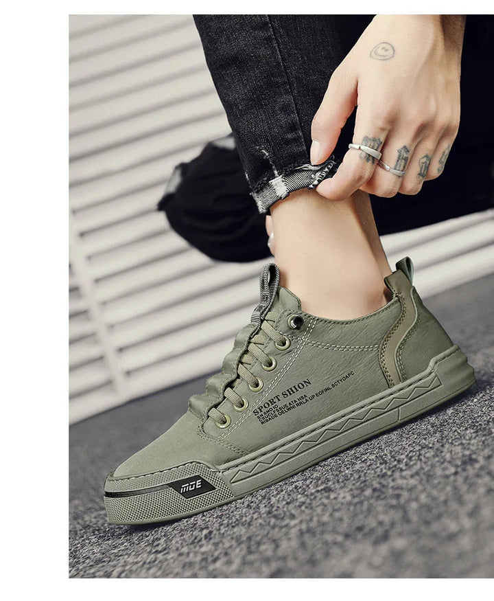 Person wearing olive green casual sport shoes with laces and decorative text, paired with black distressed jeans