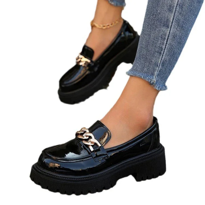 Black patent leather platform loafers with gold chain detail worn with frayed hem blue jeans