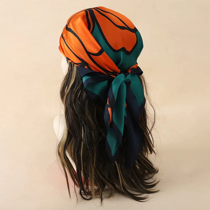 Long wavy hair with orange and green patterned silk scarf tied at back on beige background