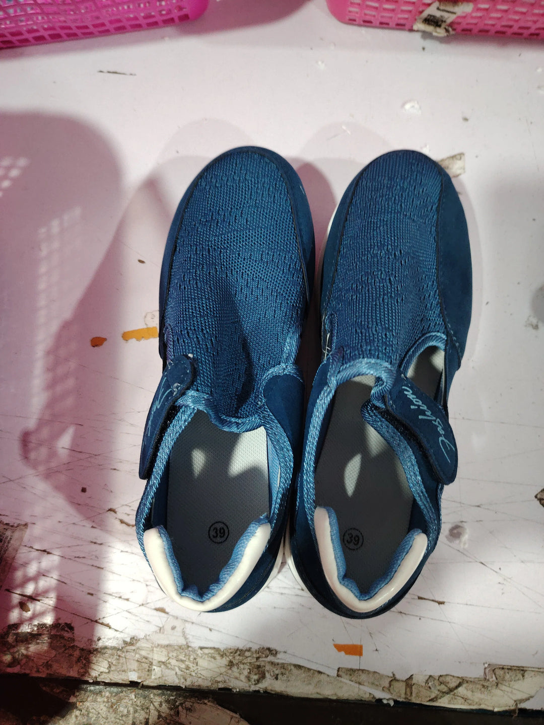 Pair of blue breathable mesh slip-on shoes with velcro straps on a white surface