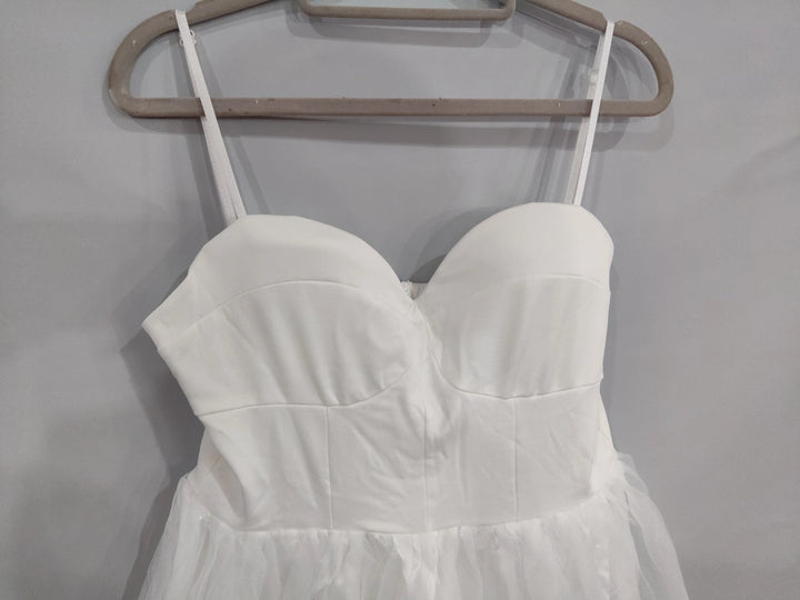 White sleeveless dress with fitted bodice and tulle skirt hanging on wooden hanger