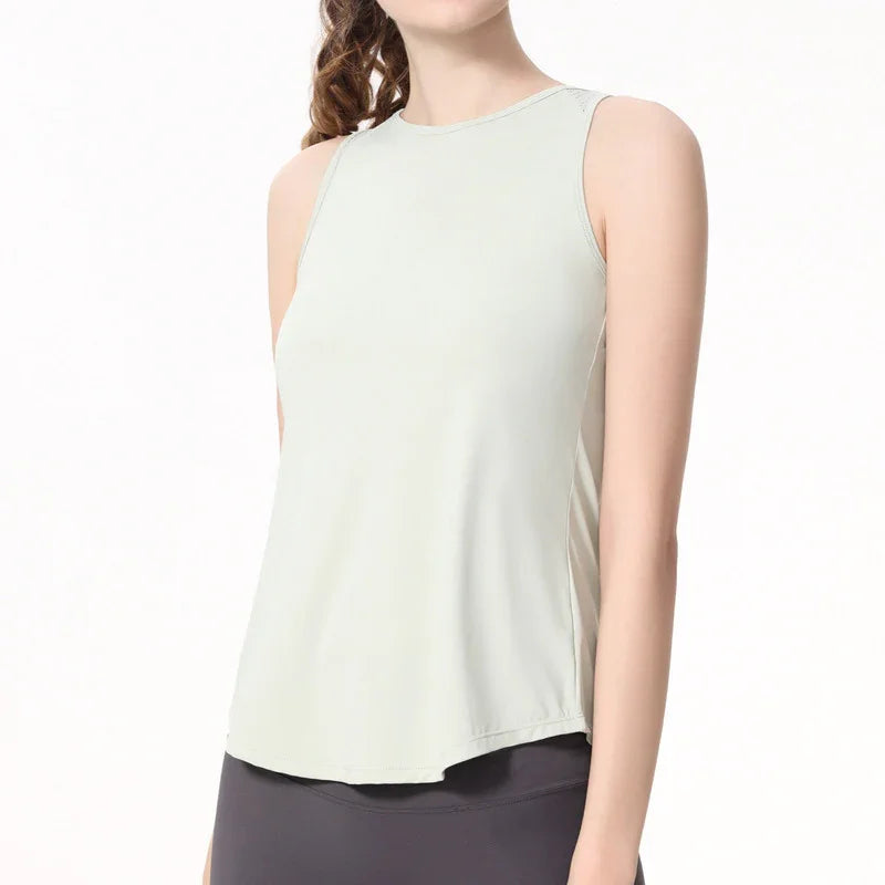 Woman wearing sleeveless light beige tank top and black leggings on white background