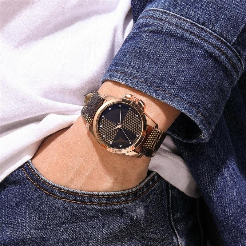 Close-up of a wrist wearing a stylish gold case watch with a black patterned dial and fabric strap paired with denim jacket and jeans