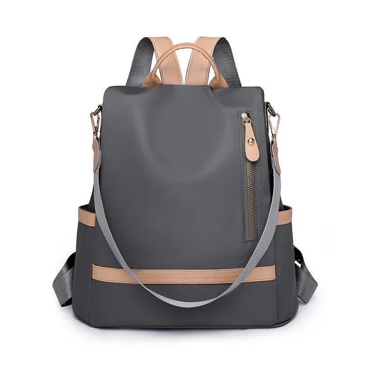 Gray backpack with beige leather accents, front zipper pocket, and adjustable shoulder straps