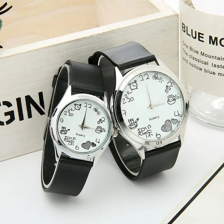 Pair of analog quartz watches with black leather straps and white dials featuring playful doodle hour markers