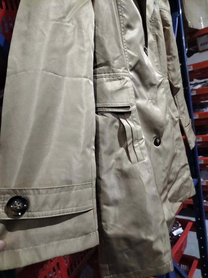 Close-up of beige trench coat with buttoned cuff and flap pocket in retail clothing warehouse