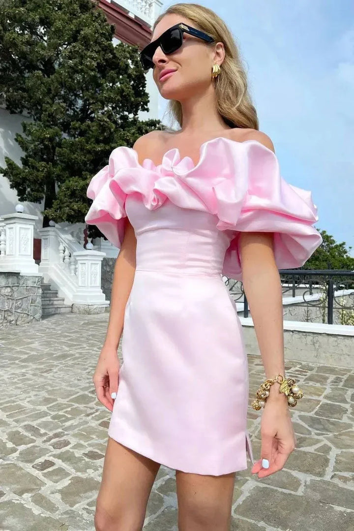 Woman wearing a pink off-shoulder ruffled mini dress with black sunglasses and gold jewelry outdoors