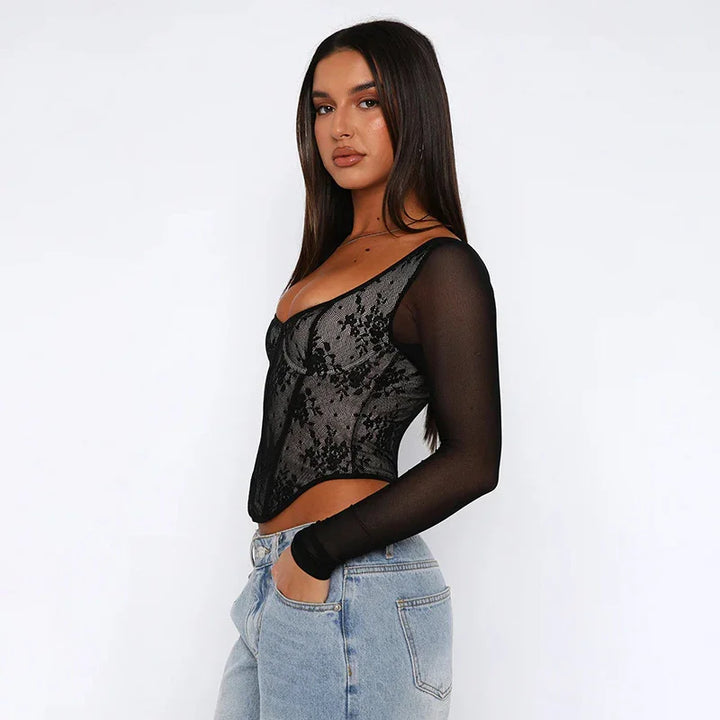 Woman wearing black lace sheer long-sleeve top and light blue denim jeans against white background