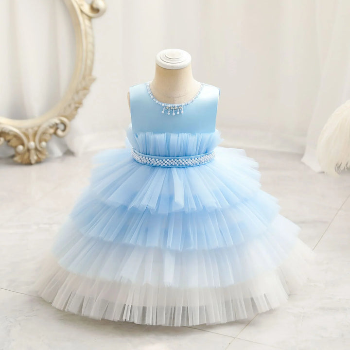 Blue and white layered tulle flower girl dress with pearl embellishments on a mannequin