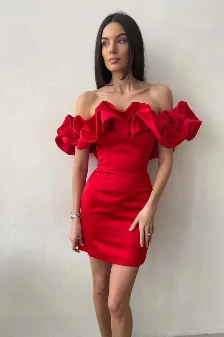 Woman wearing a vibrant red off-shoulder mini dress with ruffled neckline against plain wall