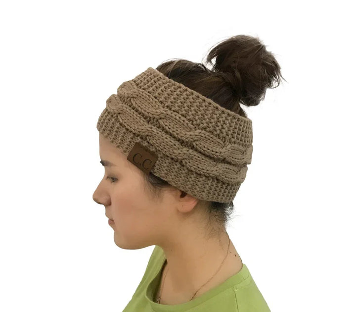 Woman wearing tan cable knit winter headband with bun hairstyle, green shirt, white background