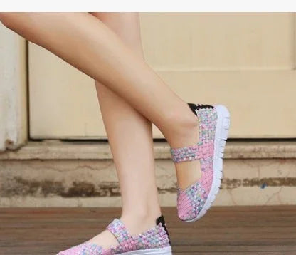 Close-up of legs wearing pink woven casual slip-on shoes with white soles on wooden floor