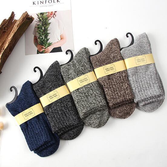 Set of five cozy ribbed wool socks in navy, black, gray, brown, and light gray arranged on white background with Kinfolk magazine