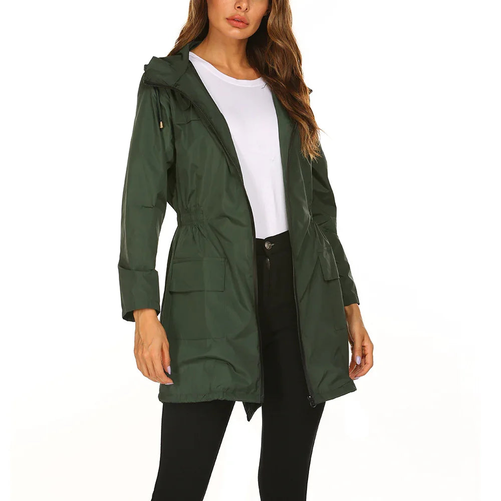 Woman wearing dark green hooded rain jacket with pockets over white t-shirt and black pants