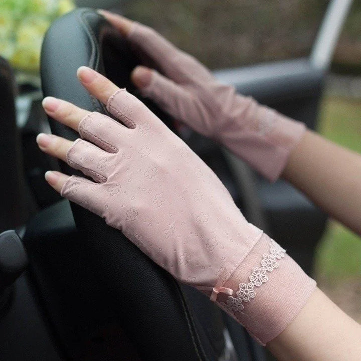 hands wearing pink floral lace fingerless driving gloves on a black steering wheel